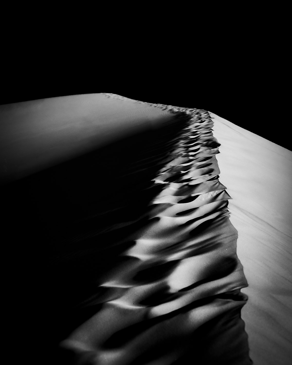 minimal black and white landscape fragment showing a sharp crest line in hard side light